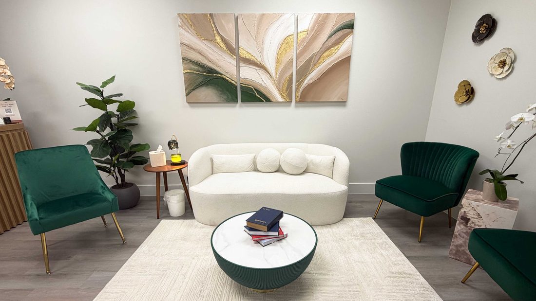 The waiting room at ZN Dermatology with green velvet chairs, a cream sofa and abstract artwork
